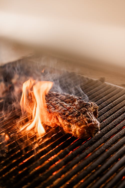 Juicy burger patty grilling on open flame BBQ