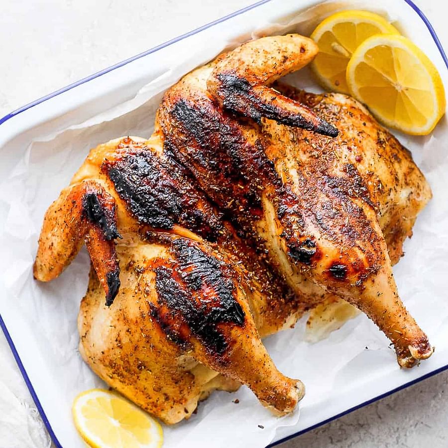 A perfectly grilled whole chicken resting on a barbecue grill